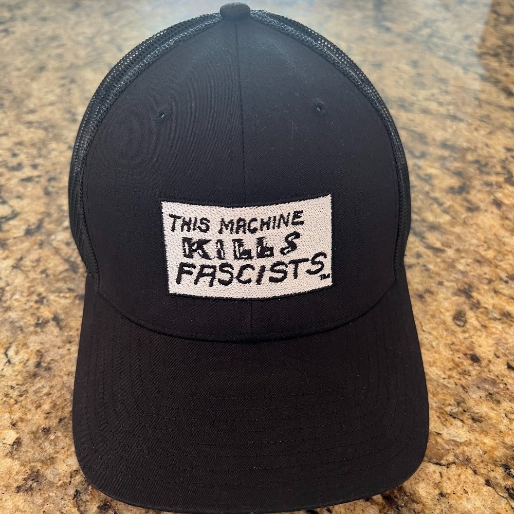 Woody Guthrie 'This Machine Kills Fascists' black trucker hat